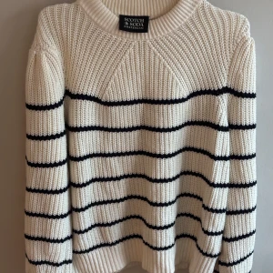 Randig stickad tröja Scotch & Soda - Säljer en chunky stickad tröja från Scotch & Soda i vitt med svarta horisontella ränder. Tröjan har bred ribbad krage, muddar och lång ärm. Perfekt för dig som gillar en klassisk men ändå trendig look.