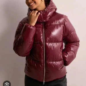 Vinröd pufferjacka med dragkedja - Snygg vinröd pufferjacka med glansig finish och hög krage. Jackan har en rak passform, lång ärm och hel dragkedja framtill. Perfekt för kalla dagar när du vill hålla stilen och värmen. Från nelly ❤️ skriv för fler bilder! Storlek: S