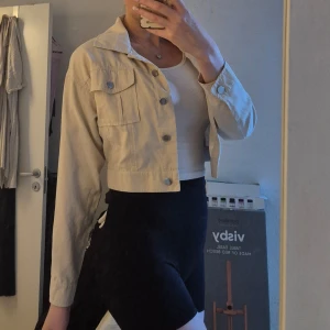 Beige croppad jacka från Boohoo - Beige, snygg croppad jacka från Boohoo. Polyester. Jackan har klassisk krage, två bröstfickor med knappar och långa ärmar. Stängs med silvriga knappar framtill. Använd en gång. 