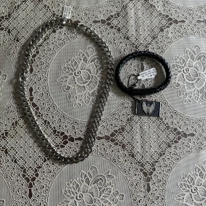 Chunky silverkedja & svart läderarmband - Säljer ett chunky halsband i silverfärgad metall med breda länkar och ett svart flätat armband i läderlook med metallplatta och ingraverad örn. Halsbandet har en klassisk karbinhake och armbandet är lätt att ta på. Köptes från Lyxa. Helt nya med prislapp. Säljer separat eller tillsammans. Armbandet säljes för 50:- och halsbandet för 120. Säljes tillsammans för 150:-