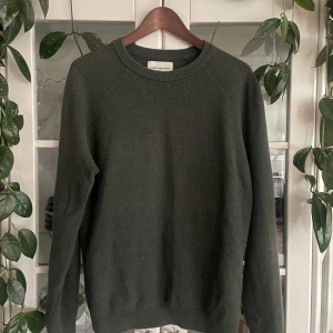 Mörkgrön tröja från These Glory Days - Säljer en stilren mörkgrön stickad tröja från These Glory Days. Tröjan har rund halsringning, ribbade muddar och är långärmad. Perfekt för lager-på-lager och funkar året runt. Enkel att matcha med jeans eller chinos.