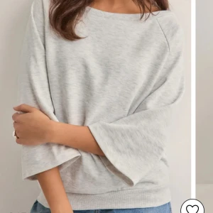 nelly tröja  - Supermjuk ljusgrå sweatshirt med avslappnad passform och trekvartsärmar. Tröjan har rund halsringning och är tillverkad i bomullsmix som känns skön mot huden. Perfekt till jeans för en chill look. enbart använd 1 gång 