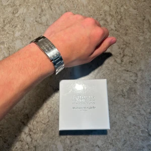 Maison Margiela silver armband - Snyggt armband från Maison Margiela i blankt silverfärgat metall med deras ikoniska siffror ingraverade på plattan. Länkarna är robusta och ger en clean, modern vibe. Kommer med original ask. 