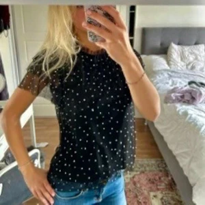 Mest topp med stenar  - Svart topp i mesh med strasstenar. Den har rund halsringning med volang och finns en knapp i ryggen som man kan knäppa. Säljer då den inte kommer till användning!🩷