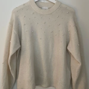 Beige stickad tröja med pärlor H&M - Superfin vit stickad tröja från H&M med pärldetaljer över hela framsidan och ärmarna. 