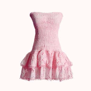 Rosa axelbandslös volangklänning - Supersöt rosa kortklänning med smockad överdel och volangig kjol. Axelbandslös modell med broderade detaljer och luftig känsla, perfekt för varma dagar. Klänningen har en feminin och lekfull stil som verkligen sticker ut.