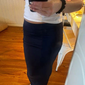 Mörkblå långkjol i stretchigt tyg - Säljer en stilren mörkblå långkjol med tight passform. Kjolen är enkel och utan mönster, perfekt för dig som gillar en clean look. Materialet är stretchigt och följsamt, vilket gör den bekväm att bära hela dagen.