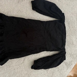 Svart kort klänning från BikBok - Supersnygg svart kort klänning från BikBok i storlek XS. Klänningen har långa puffärmar och är figurnära med fina broderade detaljer i tyget. 