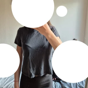 Svart croppad t-shirt från SOC - En svart, enkel och croppad t-shirt från SOC i storlek XS. T-shirten har korta ärmar och en avslappnad passform. Perfekt till jeans eller kjol för en chill look. Materialet känns mjukt och lätt mot huden.