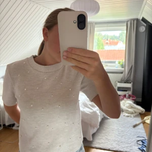 Beige stickad topp med pärlor från Zara - Superfin beige stickad topp från Zara med korta ärmar och rund hals. Toppen är dekorerad med små pärlor framtill. Pris kan diskuteras