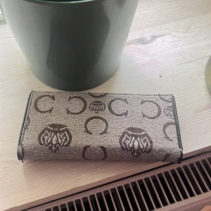 Vintage plånbok - Snygg plånbok i brunt med fina mönster och detaljer i ormskinnslook samt nitar och spänne. Flera fack för kort och ID, perfekt för att hålla ordning på allt viktigt. Materialmix av textil och skinnimitation. Pris kan diskuteras 