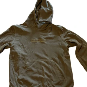 Olivgrön hoodie från Peak Performance - Snygg olivgrön hoodie från Peak Performance med broderad logga på bröstet. Tröjan har huva med snörning och en stor magficka framtill. Perfekt för en avslappnad och cool stil.