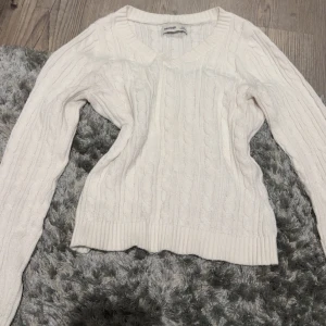 Vit kabelstickad tröja Hollister - Vit kabelstickad tröja från Hollister i storlek XXS. Tröjan har v-ringning och långa armar. Den har används några gånger men finns inga täcken på användning!