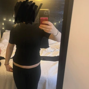 Svart polotopp från Bik Bok - En svart polotopp från Bik Bok med korta ärmar och tight passorm. Materialet är ribbat på utsidan av tröjan och stretchigt vilket gör den skön att ha på sig. Är supersnygg till alla tillfällen!💕