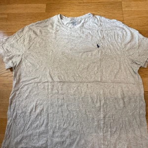 Grå t-shirt från Polo Ralph Lauren XL - Snygg grå t-shirt från Polo Ralph Lauren i klassisk passform. T-shirten har korta ärmar, rund halsringning och den ikoniska broderade loggan på bröstet. Tillverkad i mjuk bomull som är skön att bära hela dagen.