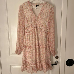 Blommig klänning från Vero Moda - Jättefin klänning från Vero Moda med blommigt mönster. Klänningen har volangdetaljer, v-ringning och långa ärmar. Perfekt för vår och sommar, lätt och luftig. Storlek XS, bara använd en gång💗