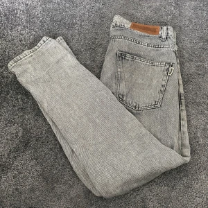 Grå jeans från Woodbird - Snygga grå jeans från Woodbird med klassisk femficksdesign och raka ben. Jeansen har en ljusgrå tvätt och råa kanter nertill för en avslappnad vibe. Hör av dig vid frågor