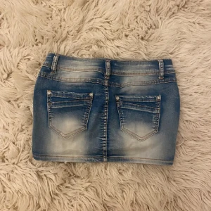 Blå jeanskjol med slitningar - INTRESSEKOLL Snygg kort jeanskjol i blå denim med slitna detaljer och fyra knappar framtill. Kjolen har klassiska fickor både fram och bak samt bälteshällor. Perfekt för en cool och avslappnad stil. storlek m men är mer xs ❤️stretchig