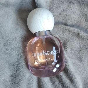 Cloudscape parfym från Rituals 15ml - Cloudscape eau de parfum från Rituals i en söt, rund glasflaska med ljuslila ton och en stor, vit träliknande kork. Flaskan rymmer 15 ml och har en stilren, modern design som känns både fräsch och trendig.