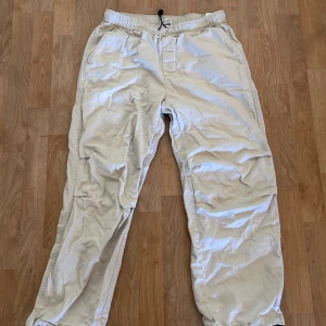 Beiga linnebyxor från Only & Sons - Snygga beiga linnebyxor från Only & Sons med avslappnad passform. Byxorna har elastisk midja med snörning och dragsko i benslut. 