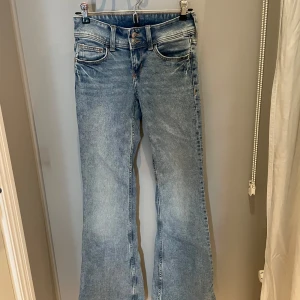 Lågmidjade blå bootcut jeans med broderade fickor - Snygga ljusblå bootcut jeans från H&M med broderade bakfickor. Lågmidja!!! Jag är 165 och sitter bra i benlängden. 