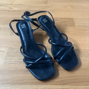 Svarta klackskor - Stilrena svarta klackskor från Skopunkten med smala remmar och fyrkantig tå. Skorna har låg klack och justerbar rem runt ankeln. Perfekta för dig som gillar minimalistisk och trendig design. Endast använda en gång