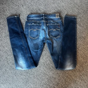 Ljusblå Replay Jeans  - Snygga blå skinny jeans från Replay med coolt broderi på bakfickorna och slitna detaljer. Jeansen har klassisk femficksdesign, dragkedja och knapp framtill. Perfekt passform och stretchigt material som gör dem riktigt bekväma.