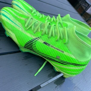 Nike Mercurial Dream Speed fotbollsskor - Säljer ett par grymt snygga Nike Mercurial Dream Speed fotbollsskor i neon-grönt med svarta detaljer och coola ränder. Skorna har snörning, hög krage och är tillverkade i syntetmaterial för bästa känsla på planen.