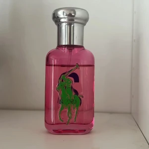 Ralph Lauren Big Pony 2 Pink Parfym - Cool parfym från Ralph Lauren Big Pony Collection, nummer 2. Flaskan är rosa med blå och grön logga och har ett silvrigt lock. Perfekt för dig som gillar färgstark design och fräscha dofter. Flaskan är i glas och har en modern, sportig look.