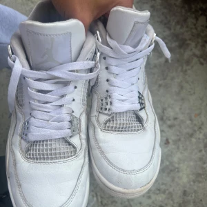 Nike Air Jordan 4 Retro pure money - Säljer ett par Nike Air Jordan 4 Retro i helvitt skinn med vita meshpaneler och silvriga detaljer vid snörningen. Klassisk Jumpman-logga på hälen och plös. Snygg chunky sula och ikonisk design som sticker ut.
