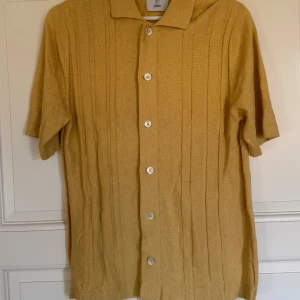 Gul stickad kortärmad skjorta från Bläck - Säljer en gul stickad skjorta från Bläck då den inte används längre då den har blevit för liten. Perfekt inför sommaren med färgen och passform. 