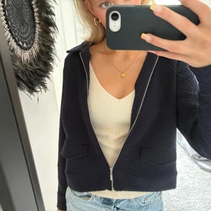 Mörkblå quiltad jacka med dragkedja - Snygg mörkblå jacka med quiltat mönster och silverfärgad dragkedja. Jackan har två fickor framtill och en krage. ❤️