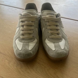 Maison Margiela Gats - Säljer ett par fina Maison Margiela Gats i färgen vit/beige, skorna är i ett väldigt bra skick lite smutsiga och en liten skavank på ena hälen, en svart fläck. Är öppen för byten och pris kan diskuteras.