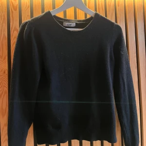 Svart stickad tröja från JDY - En svart stickad tröja från JDY i storlek S. Tröjan har rund halsringning, lätt puffade axlar och långa ärmar. Perfekt för dig som gillar en enkel men ändå trendig look. Mjuk och skön att bära under kyligare dagar. Tveka inte på att höra av dig!