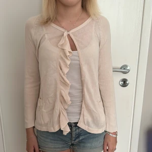 Beige kofta med volangdetaljer - Supersöt beige kofta med volang, flera lager volanger baktill. 🩷Tunn och lätt stickad med lång ärm och små fickor. Står ej storlek men skulle gissa på xs/s. Litet slitage vid lappen, se bild 3. 100% cotton💕Pris går att diskuteras.