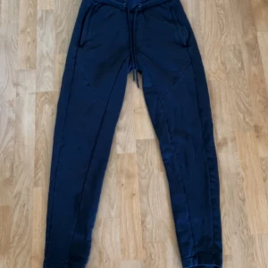 Svarta mjukisbyxor från Dressmann S - Svarta mjukisbyxor från Dressmann i storlek S. Byxorna har dragsko i midjan, två fickor fram och är tillverkade i mjukt material. Snygg och enkel design med smal passform.