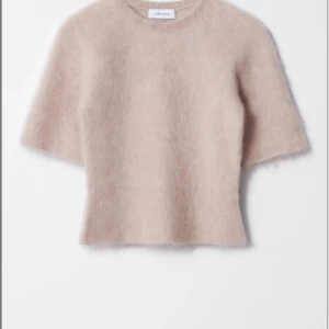 Beige stickad tröja från & Other Stories - Supermjuk och fluffig beige stickad tröja från & Other Stories. Tröjan har korta ärmar och rund halsringning, perfekt för lager på lager. Den ljusa färgen gör den enkel att matcha med allt i garderoben.