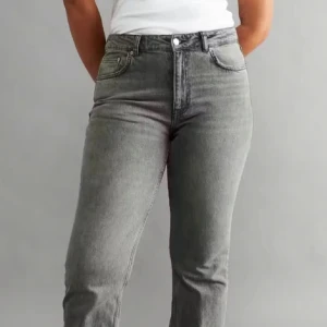 Grå bootcut jeans från Gina Tricot - Helt slutsålda, Snygga grå jeans från Gina Tricot med bootcut-modell och klassisk femficksdesign. Jeansen har hög midja och raka ben som blir vidare nedtill. Tillverkade i mjukt denimtyg med en lätt tvättad look. Perfekta för en chill och trendig stil.