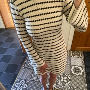 Hilma Dress SR randig klänning XS - Supersnygg kort stickad klänning i beige och svart med randigt mönster. Klänningen har lång ärm, lätt utsvängda ärmslut och en bred, öppen rygg. Figurnära passform som framhäver siluetten. Den är aldrig använd och ny pris på den är 499. Pris kan diskuteras