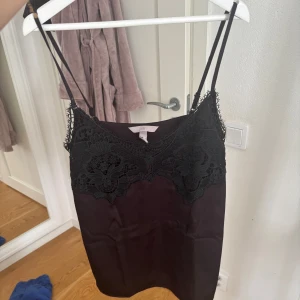 Svart spetslinne från H&M - Säljer ett svart linne från H&M med tunna axelband och snygga spetsdetaljer framtill. Strl xs. Har sytt lite på ena bandet då spetsen släppte lite. Pris 50 kr. 
