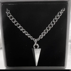 Kedjehalsband med silverfärgad spets - Stilrent halsband med grov kedja i silverfärg och en spetsig, konformad berlock. Perfekt för dig som gillar minimalistiska och edgy accessoarer. Passar till både streetwear och mer klassiska outfits.