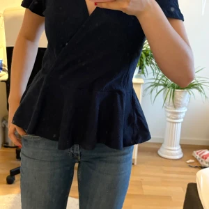 Mörkblå omlottopp från Holly & White - Supersnygg marinblå omlottopp från Holly & Whit Toppen har en markerad midja, är v ringad och har en volang. Inga defekter. Storlek M passar även s. 