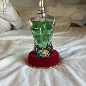 Jean Paul Gaultier Le Beau Paradise Garden 125 ml - Säljer en Jean Paul Gaultier Le Beau Paradise Garden parfym  125 ml. Flaskan är formad som en manlig torso i klart glas med grön vätska och står på en röd sammetsliknande bas med broderad detalj. Kommer med en snygg grön förpackning med färgglada blommor och drakar.