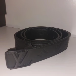 Lvbälte - Snyggt svart skärp från  i skinn med präglad -logga och ikoniskt -spänne i matt svart metall. Bältet har diskreta monogramdetaljer längs hela remmen och stilrena sömmar. Perfekt accessoar för att lyfta din outfit.