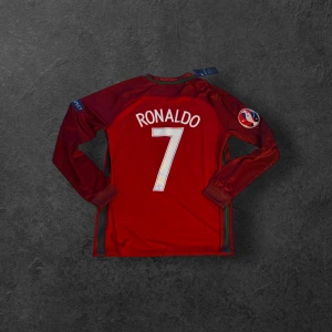 Portugal 2016 Euro Ronaldo 7 långärmad matchtröja - Portugal landslagströja från EM-finalen 2016 med Ronaldo 7 på ryggen. Röd med patchar på båda ärmarna. Info om finalen finns under portugal märket. Sällsynt att hitta en portugal tröja med final info. Oanvänd met tagg