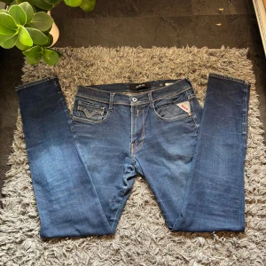 Replay anbass jeans i blå färg - Säljer ett par snygga blå jeans från Replay, modell Anbass. De har en klassisk femficksdesign med snygga sömmar på bakfickorna och en knappgylf. Perfekta för en stilren look. Skicket är super bra, hör av er vid frågor!