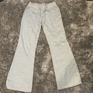 Ljusgrå mjukisbyxor med utsvängda ben - Säljer ett par ljusgrå mjukisbyxor med utsvängda ben och dragsko i midjan. Byxorna har en relaxed fit och är perfekta för en chill och avslappnad stil. Mjukt material som känns skönt mot huden.