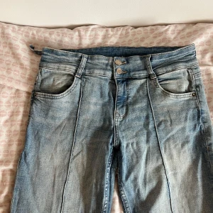 Blå bootcut jeans med pressveck - Säljer ett par blå bootcut jeans med markerade pressveck framtill. Jeansen har låg midja och en liten skada på sidan men som enkelt går att fixa. Pris kan diskuteras.