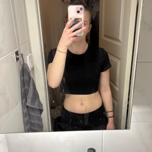 Svart croppad t-shirt - Säljer en enkel svart croppad t-shirt med rund halsringning. T-shirten har korta ärmar och är perfekt för en avslappnad stil. Passar bra till både jeans och kjol.