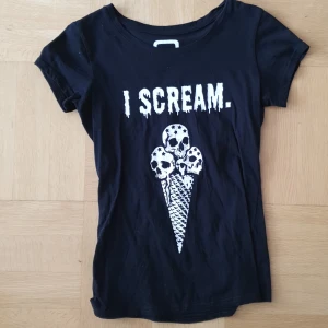 Svart t-shirt med tryck från EMP - Svart t-shirt med vitt tryck där det står 'I SCREAM.' och en glass med dödskallar. T-shirten har rund hals och korta ärmar.